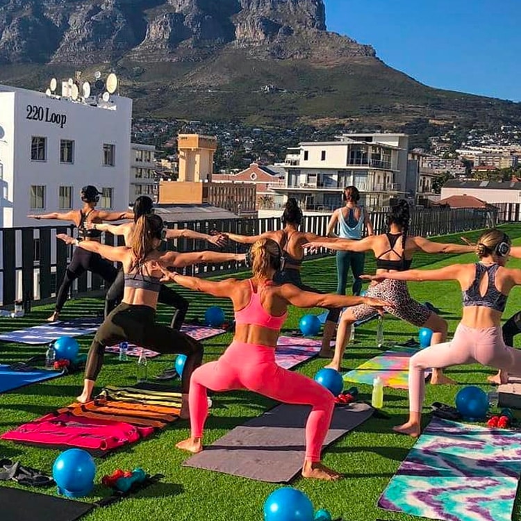 gimnasio-abierto Clase de fitness al aire libre en una terraza con auriculares inalámbricos
