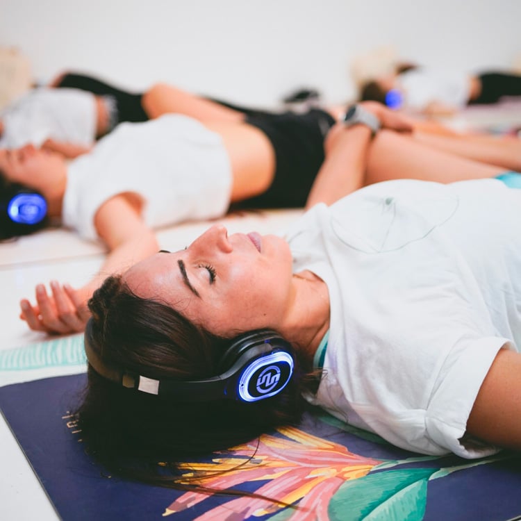 inspirafit Mujeres tumbadas con auriculares inalámbricos durante una clase de silent fitness