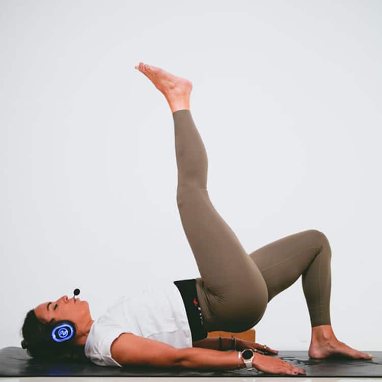 paola-inspirafit Instructora hace ejercicios en el suelo con auriculares inalámbricos