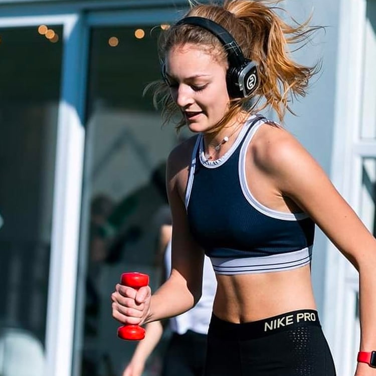 weight-capo Chica entrena con pesas con auriculares inalámbricos